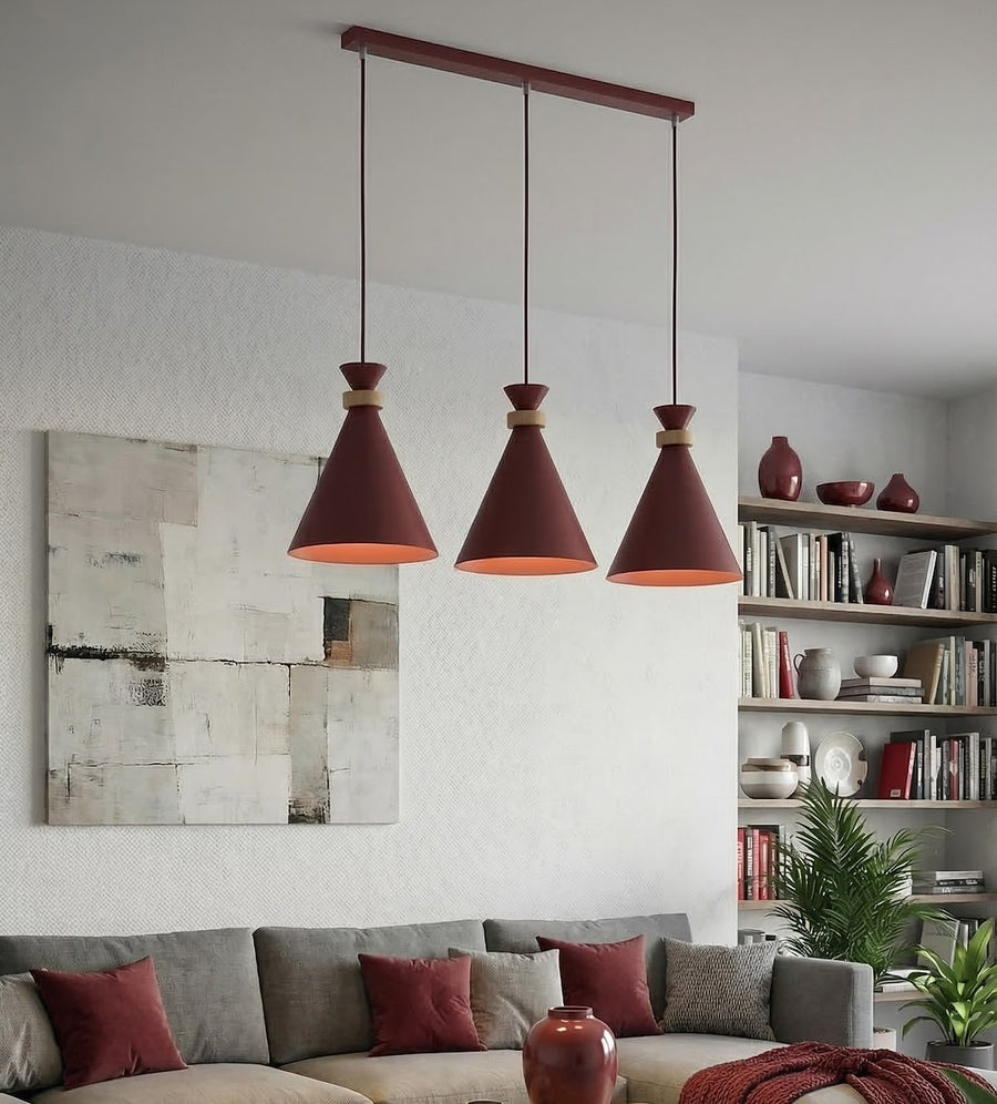 Trois cônes bordeaux suspendus devant un canapé gris dans un salon clair