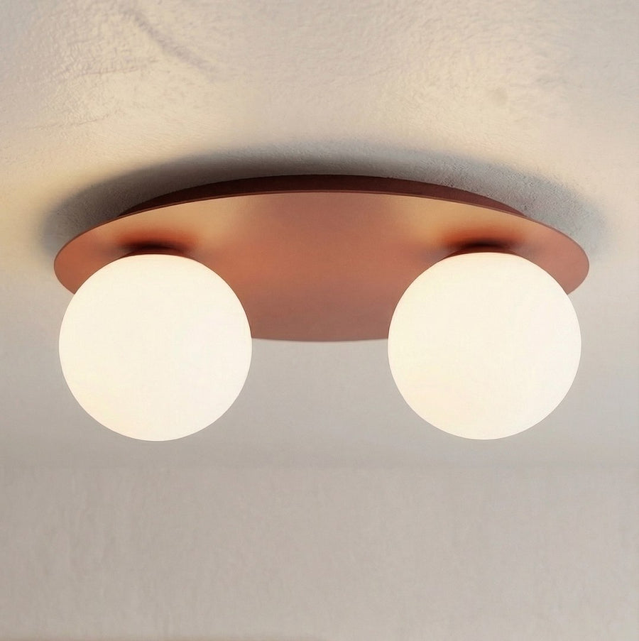Gros plan du plafonnier allumé sous plafond, platine bordeaux et globes blancs lumineux.