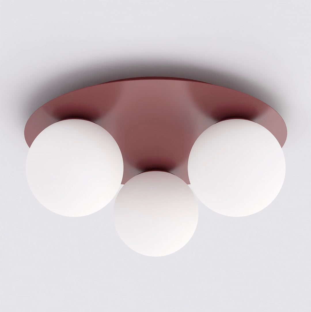 Vue de face du plafonnier bordeaux équipé de trois globes en verre blanc opalin