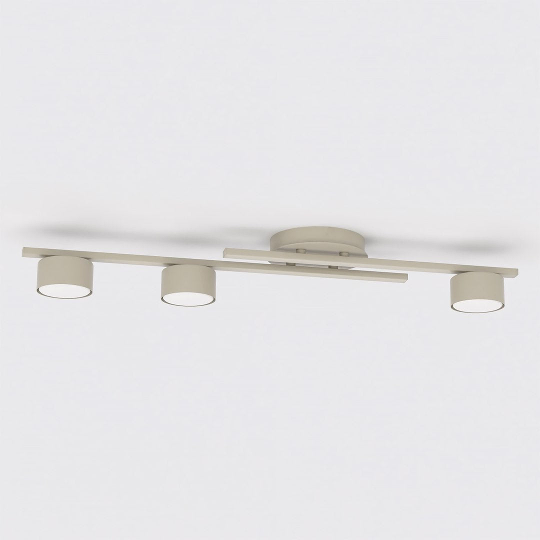 Vue de face du luminaire beige, trois têtes rondes alignées sous la barre centrale