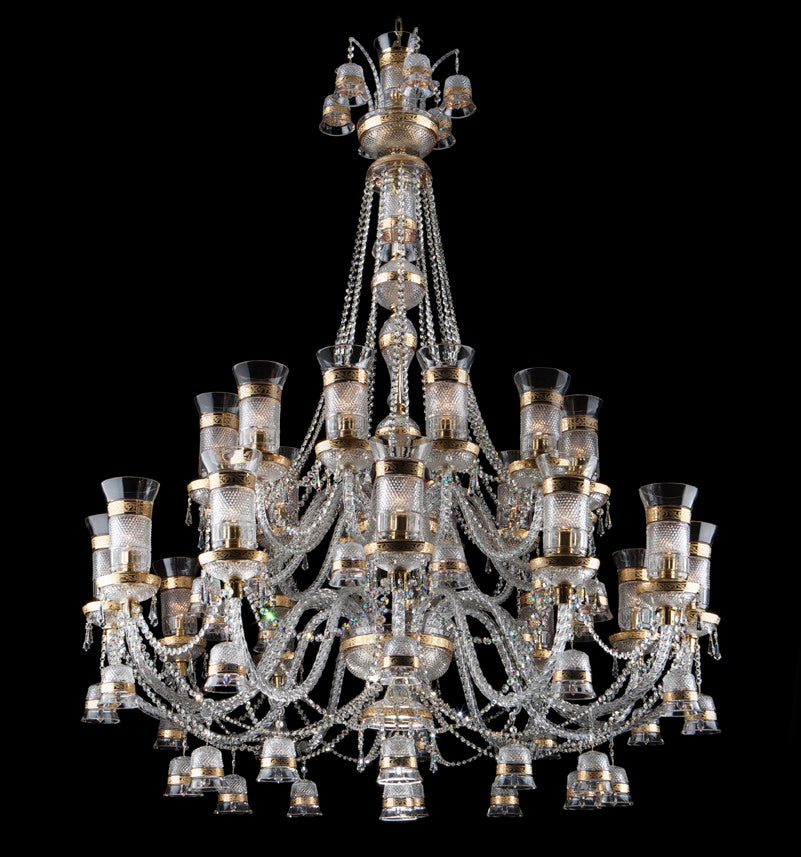 Lustre entier de face sur fond noir, cristal taillé et monture dorée, nombreux bras