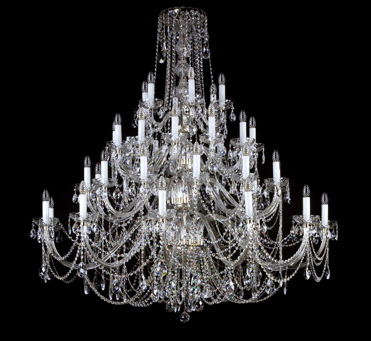 Lustre en cristal à nombreux bras, suspendu, présenté de face sur fond noir.