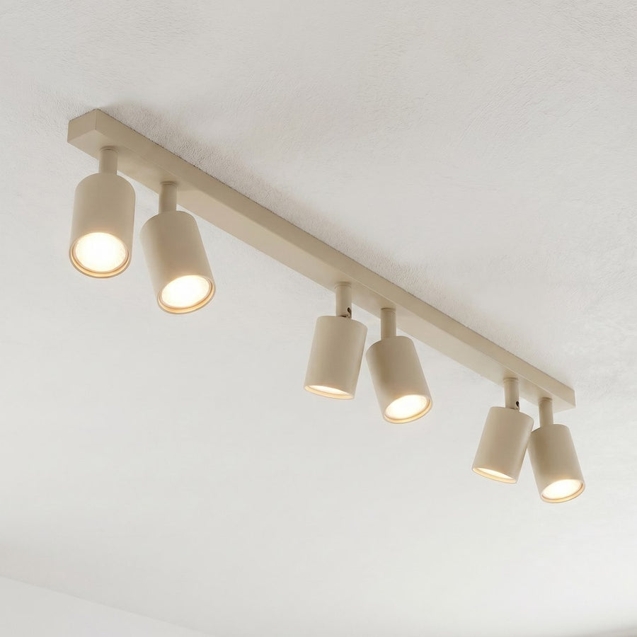 Détail rapproché des spots allumés, finition beige mate et diffuseur lumineux