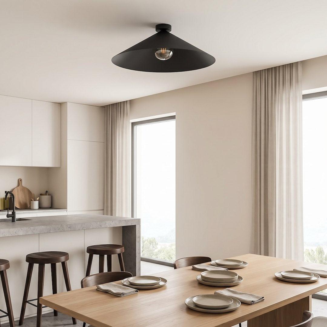 Ambiance cuisine ouverte, plafonnier conique noir au-dessus d'une table dressée près des fenêtres