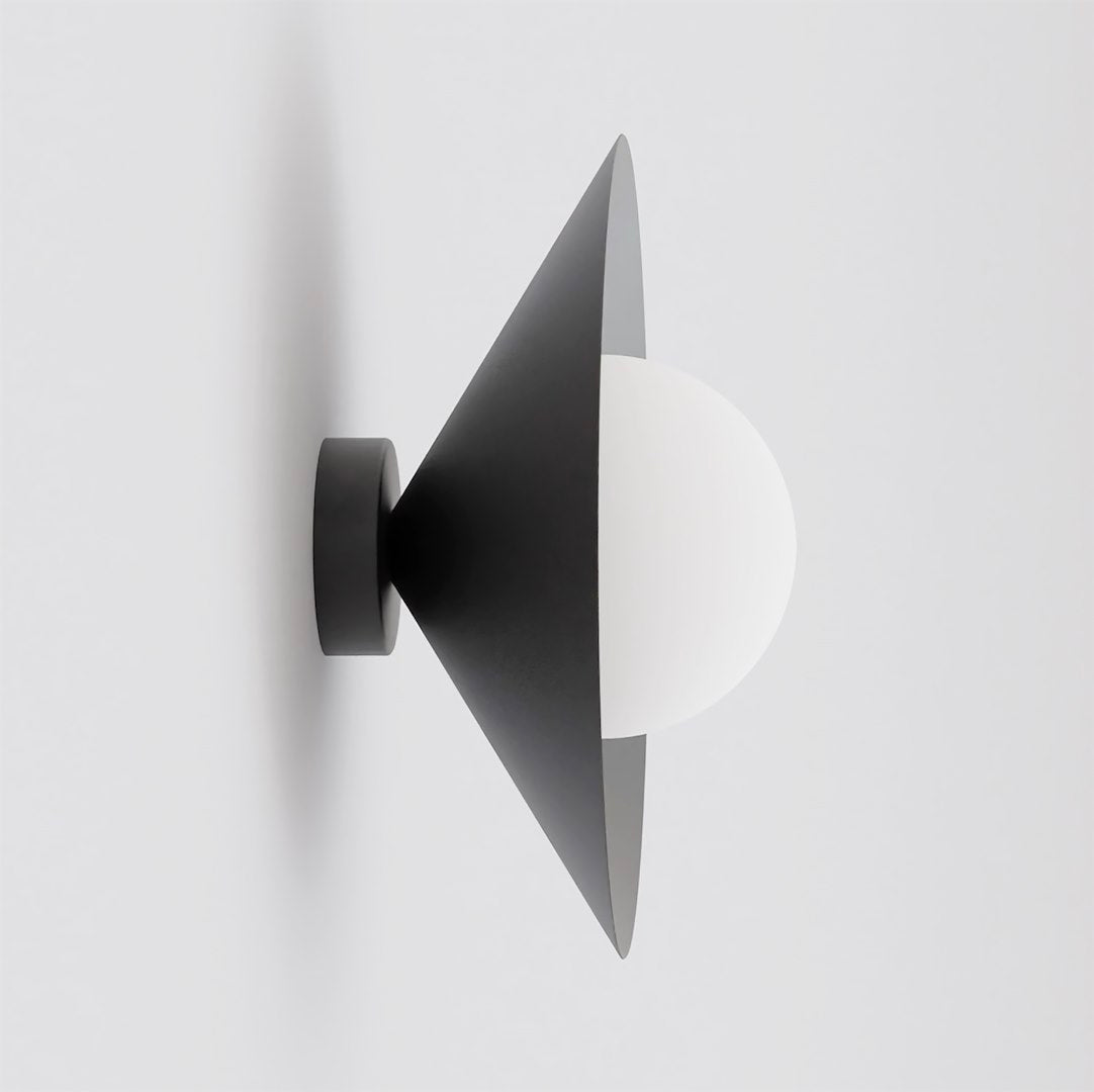 Vue de profil sur fond gris clair, applique noire au cône ouvert et diffuseur blanc.
