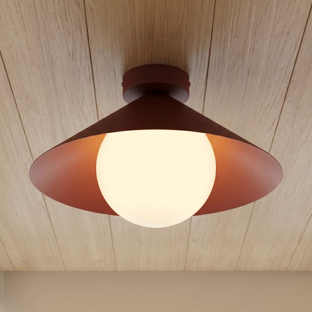 Plafonnier bordeaux allumé sous un plafond en lambris de bois clair