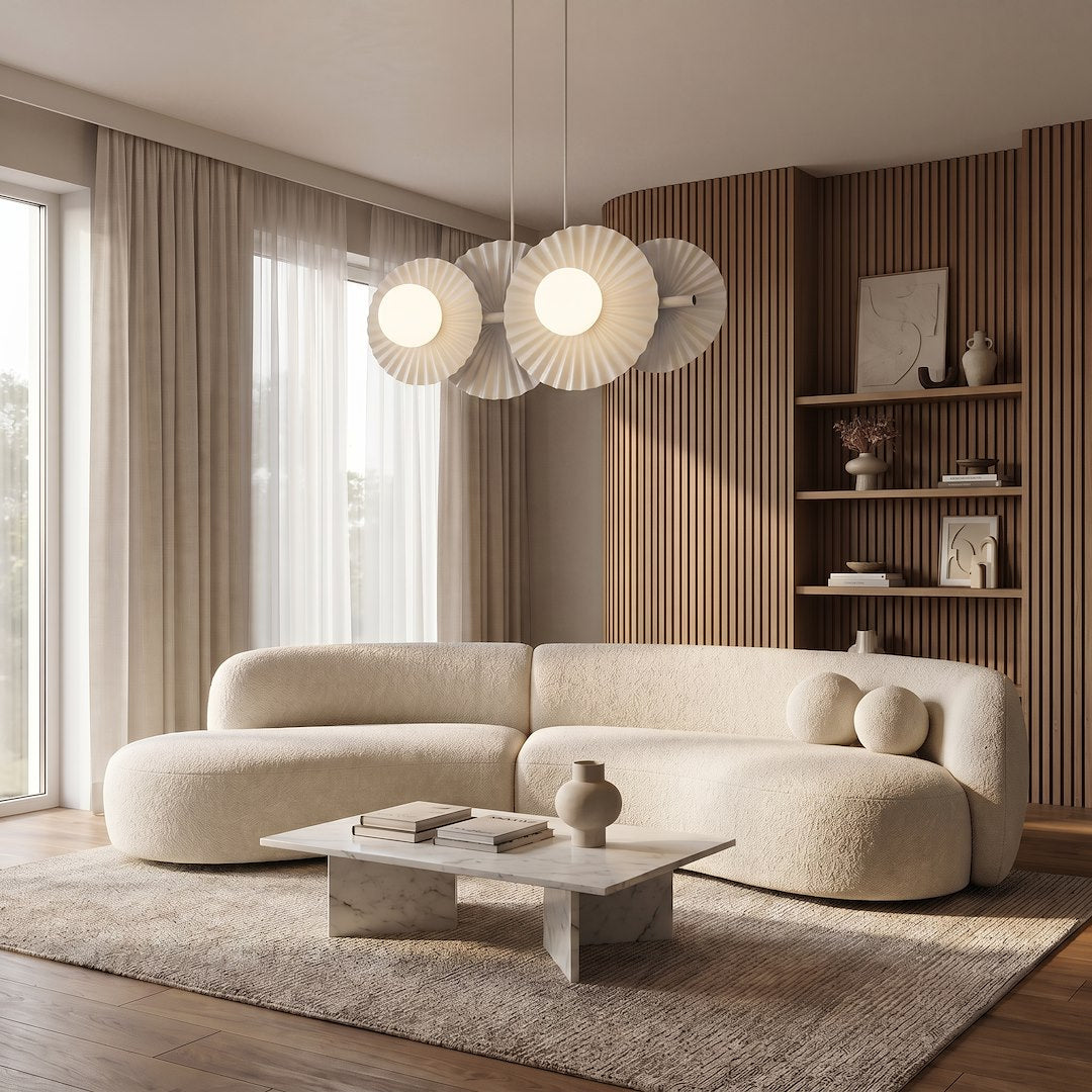 Suspension allumée au-dessus d'un salon beige, canapé bouclé et mur lambrissé en bois.