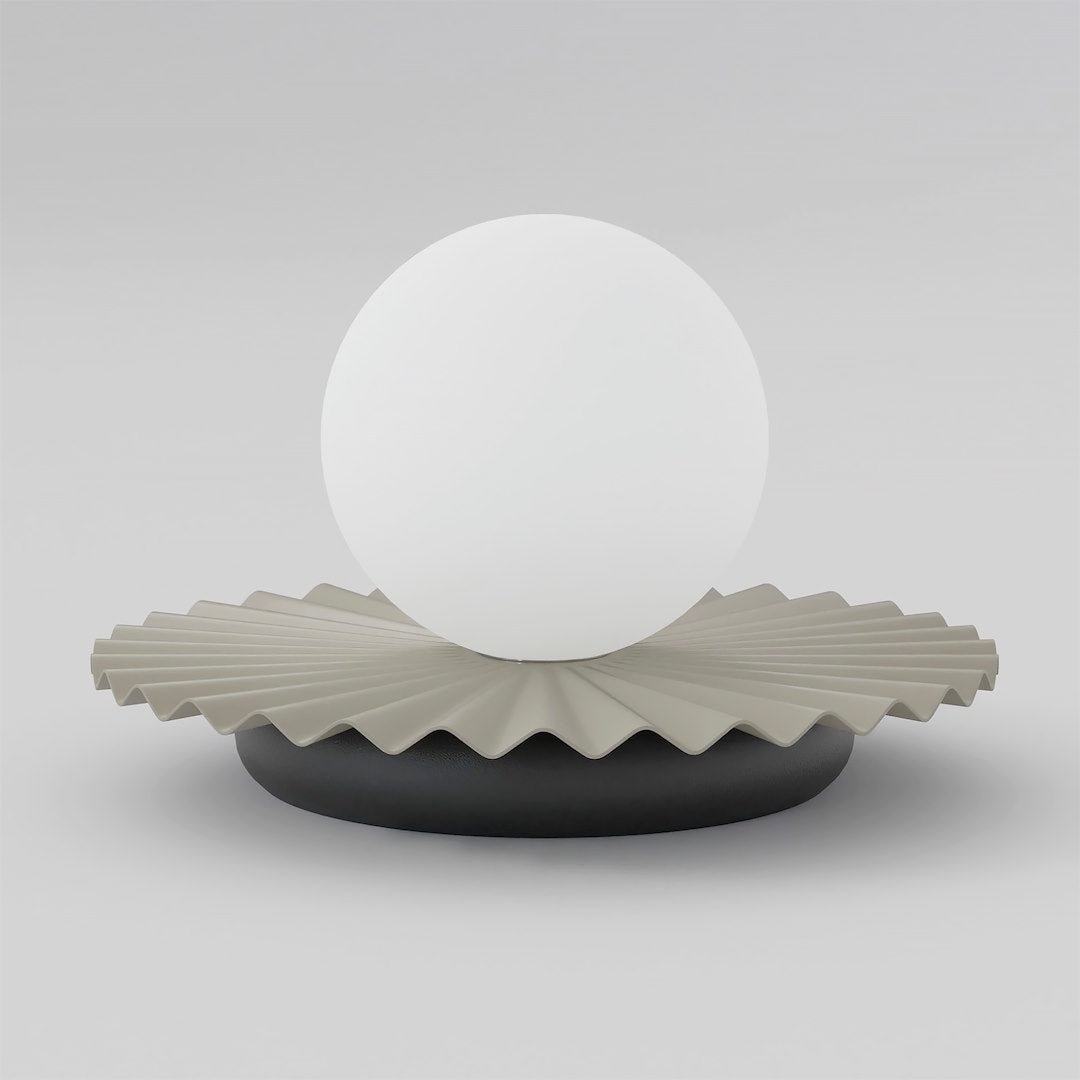 Lampe à poser de face, globe blanc en verre sur base plissée beige et socle noir.