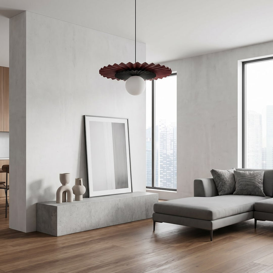 Luminaire suspendu devant un mur béton, avec cadre posé et canapé dans un intérieur épuré.