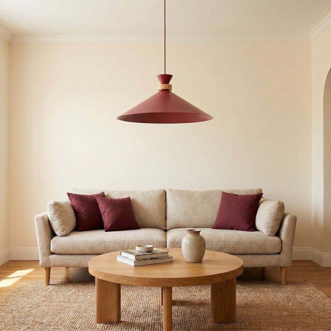 Suspension rouge foncé devant un canapé beige et une table ronde en bois