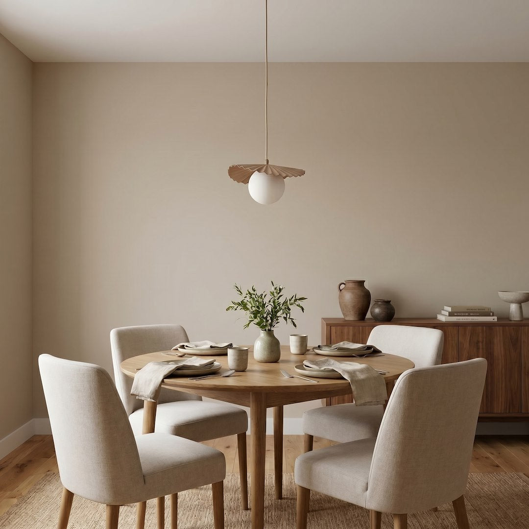 Suspension allumée au-dessus d'une table ronde en bois, dans une salle à manger beige et chaleureuse.