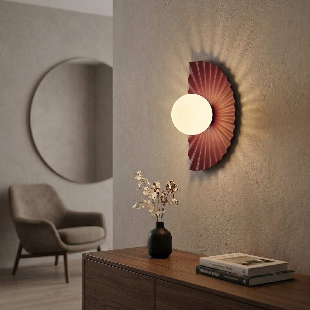 Mise en ambiance de l'applique bordeaux allumée, projetant un halo lumineux sur le mur.