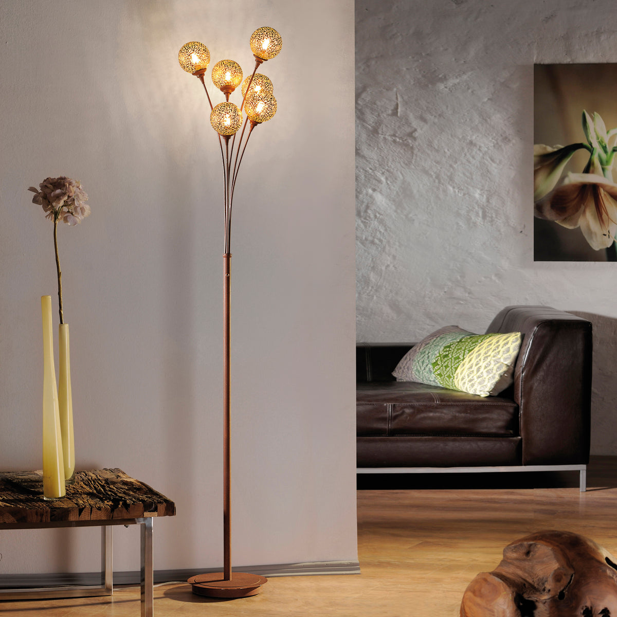 Mise en ambiance salon, lampadaire allumé près d'un canapé en cuir et tableau.