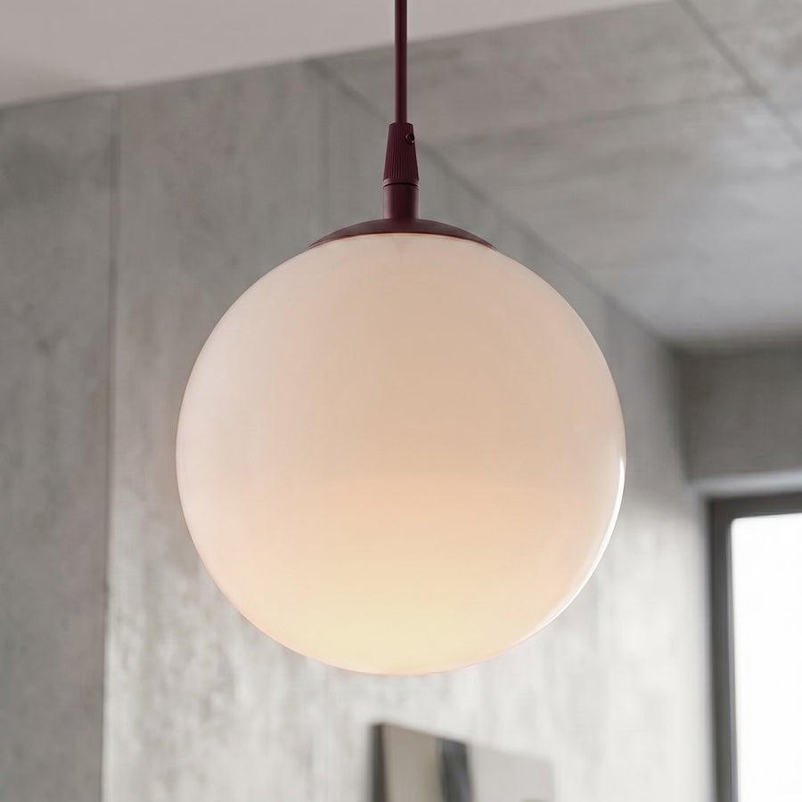 Gros plan sur le globe de verre opalin allumé et sa douille bordeaux