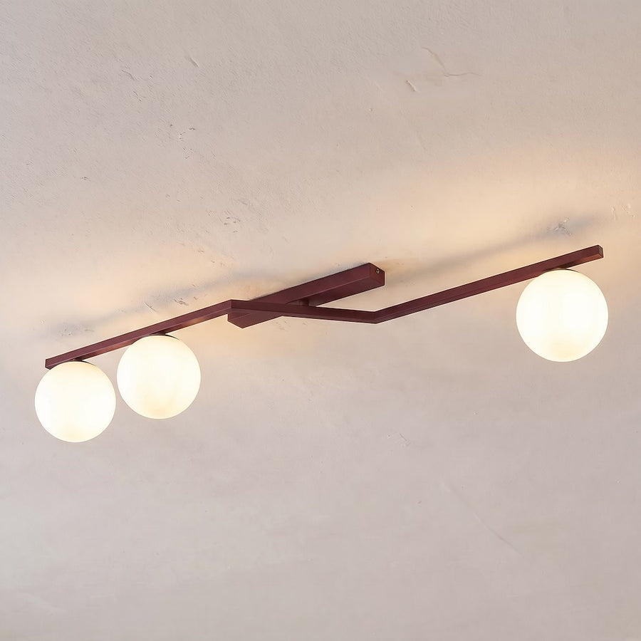 Plafonnier fixé au plafond, diffusant une lumière chaude à travers trois globes.