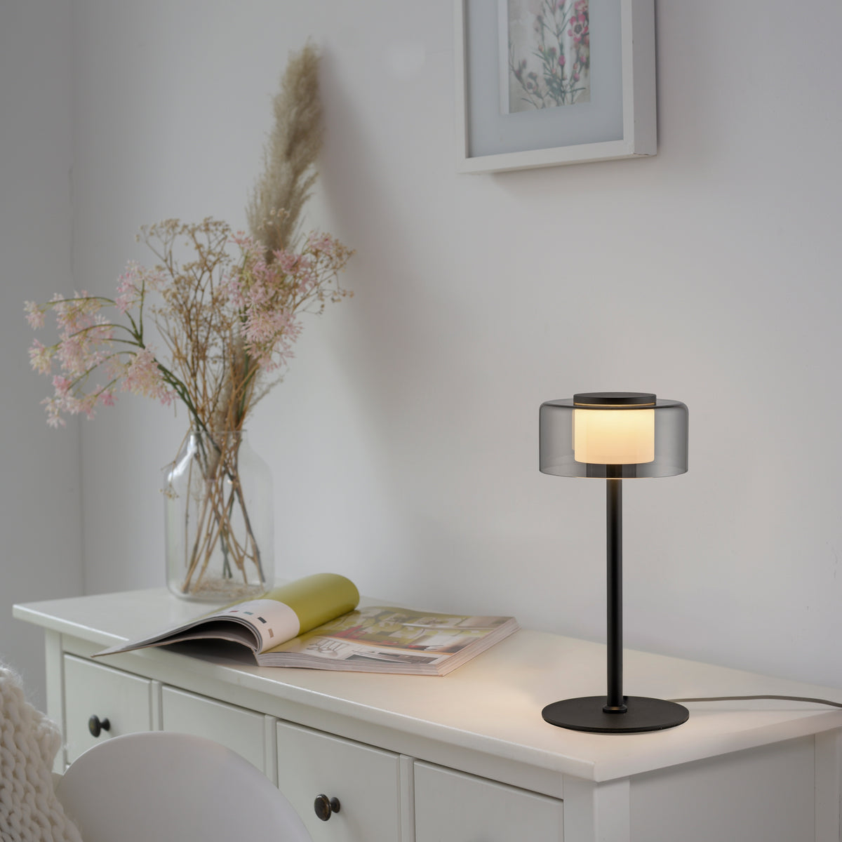 Mise en ambiance sur une commode blanche, près d'un vase de fleurs séchées