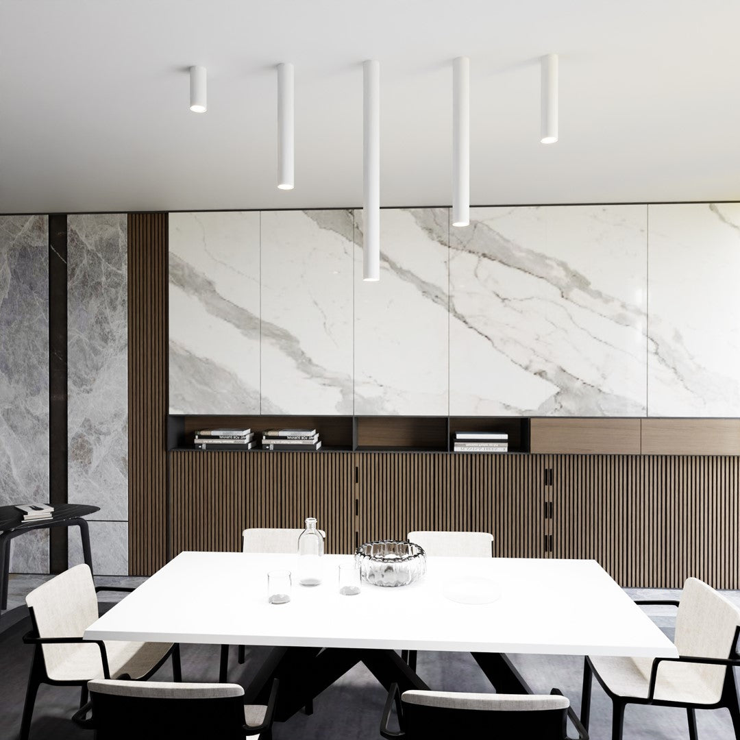 Vue large de cinq plafonniers cylindriques blancs alignés au-dessus d'une table