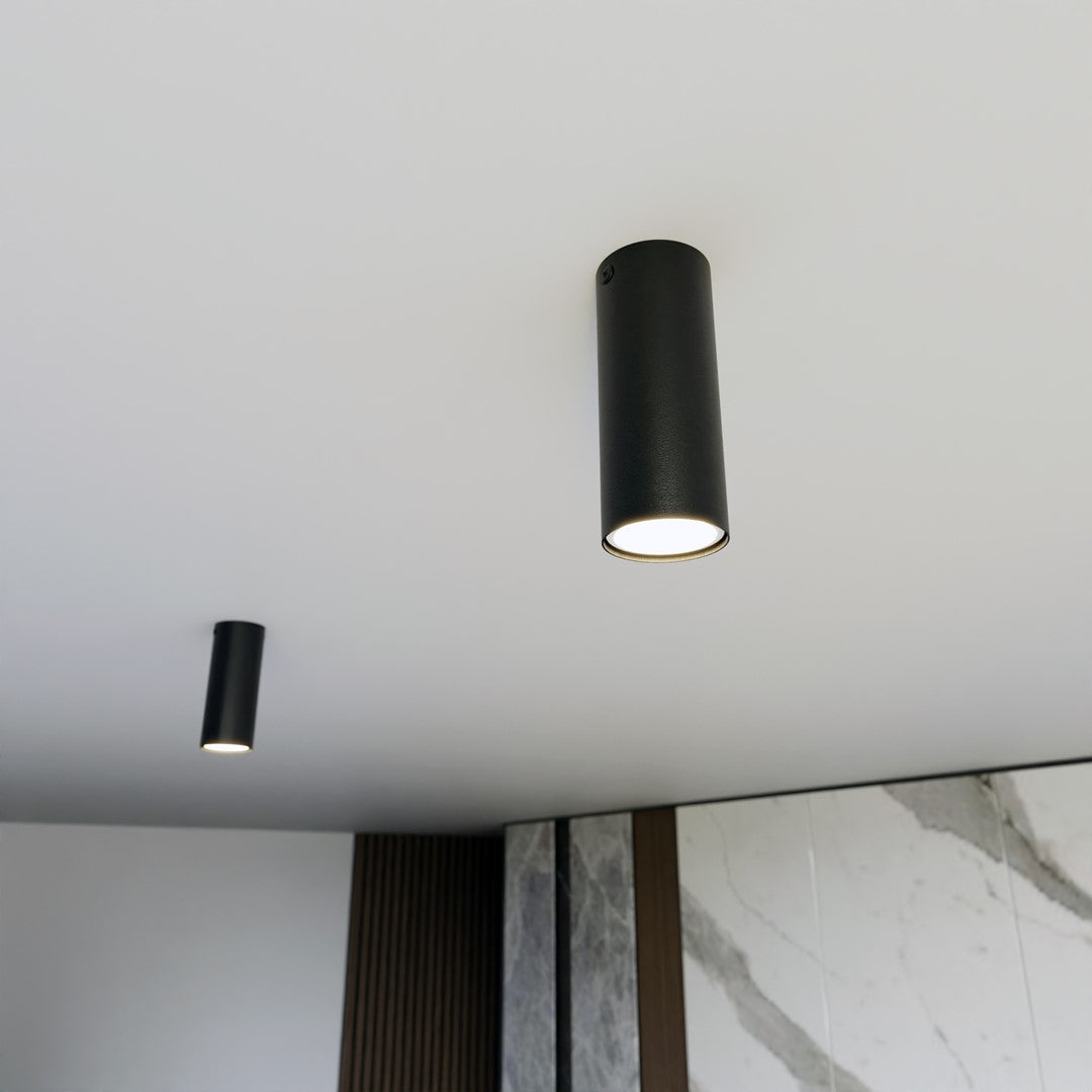 Deux spots cylindriques noirs fixés au plafond blanc d'un intérieur moderne