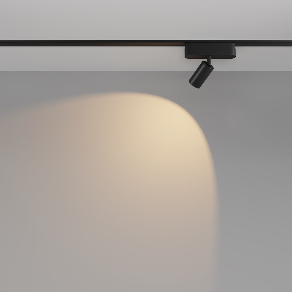 Spot projetant un halo de lumière chaude sur un mur gris clair