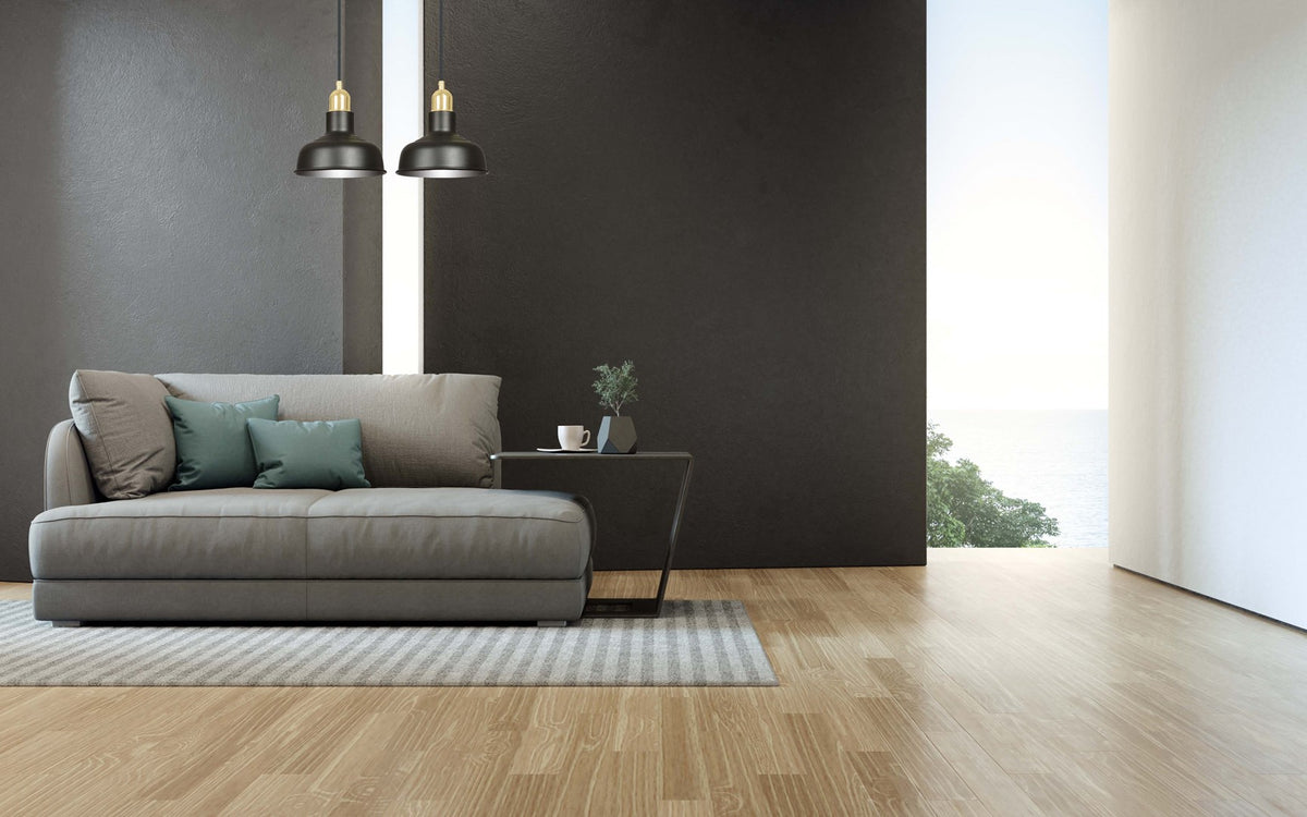 Mise en ambiance dans un salon moderne, suspension allumée au-dessus d'un canapé gris.
