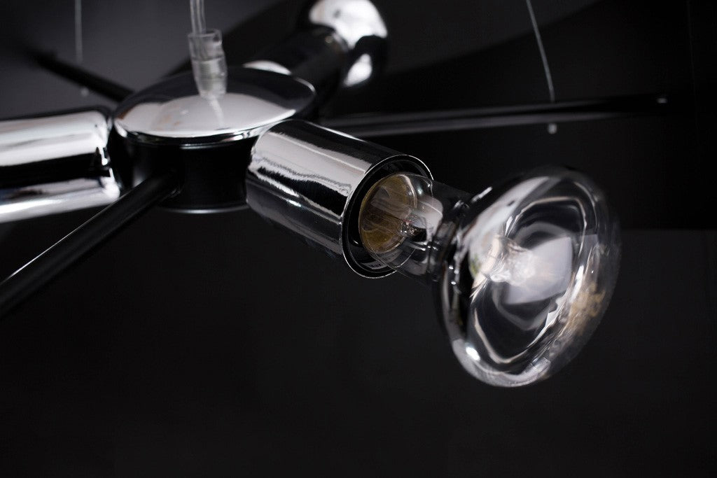 Gros plan sur une douille chromée et une ampoule transparente, fond noir