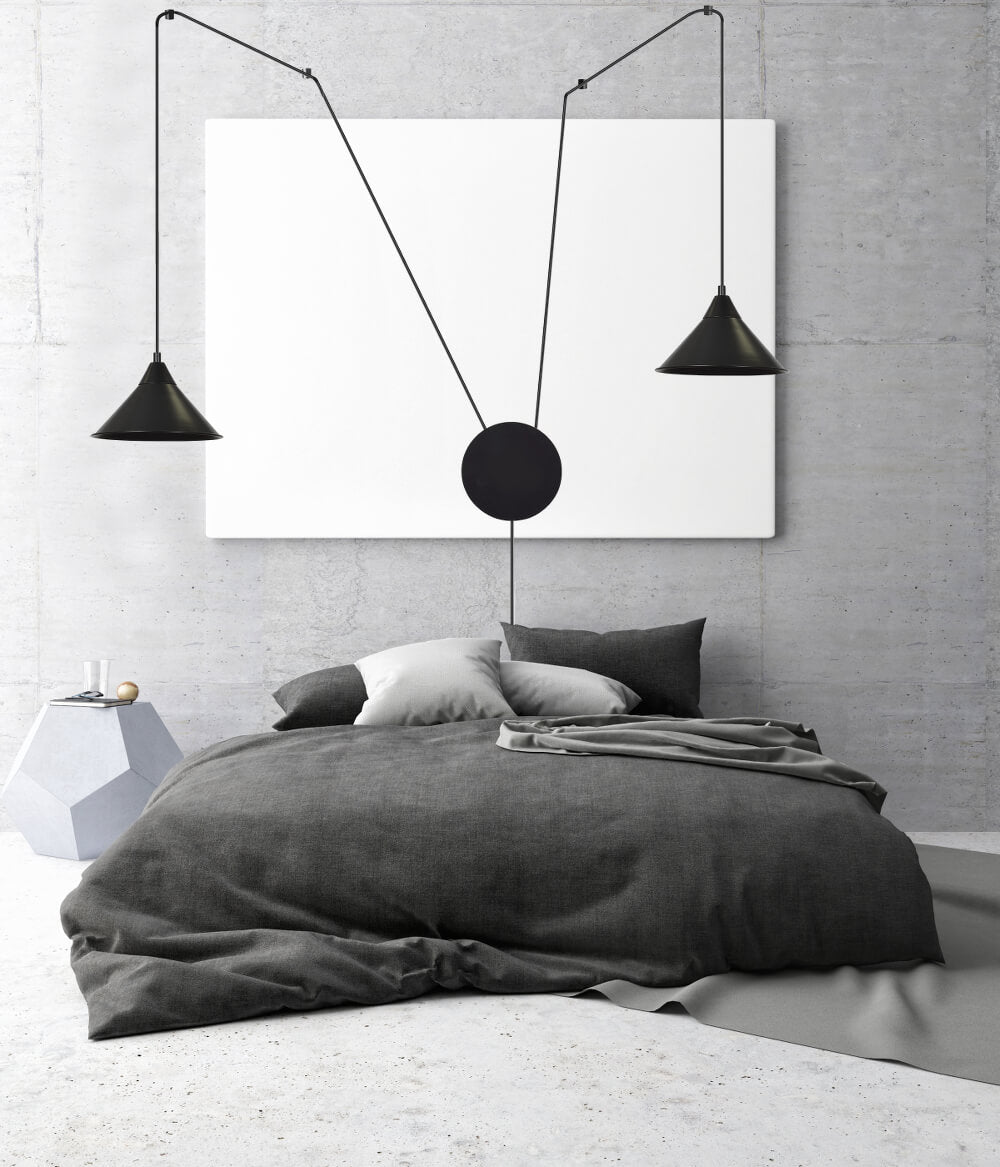 Ambiance chambre béton, suspension noire à deux abat-jours coniques au-dessus d'un lit