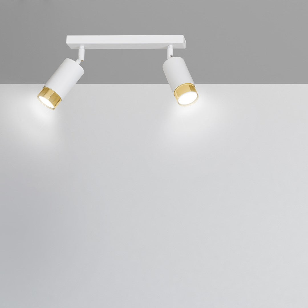 Détail de la tête orientable éclairant un mur blanc uni.