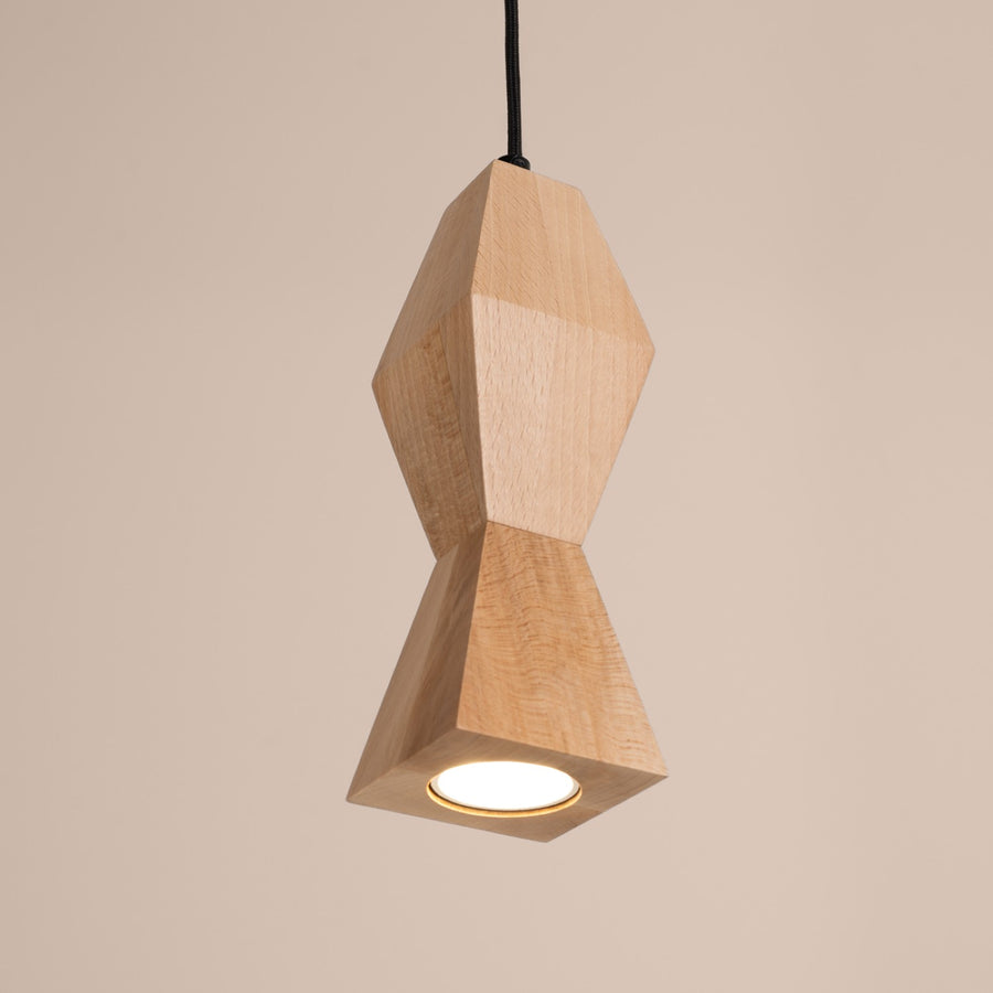 Plan rapproché du luminaire suspendu allumé, abat-jour en bois facetté et câble noir