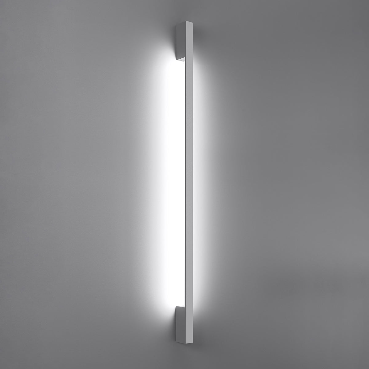 Applique allumée projetant un halo vertical lumineux sur le mur