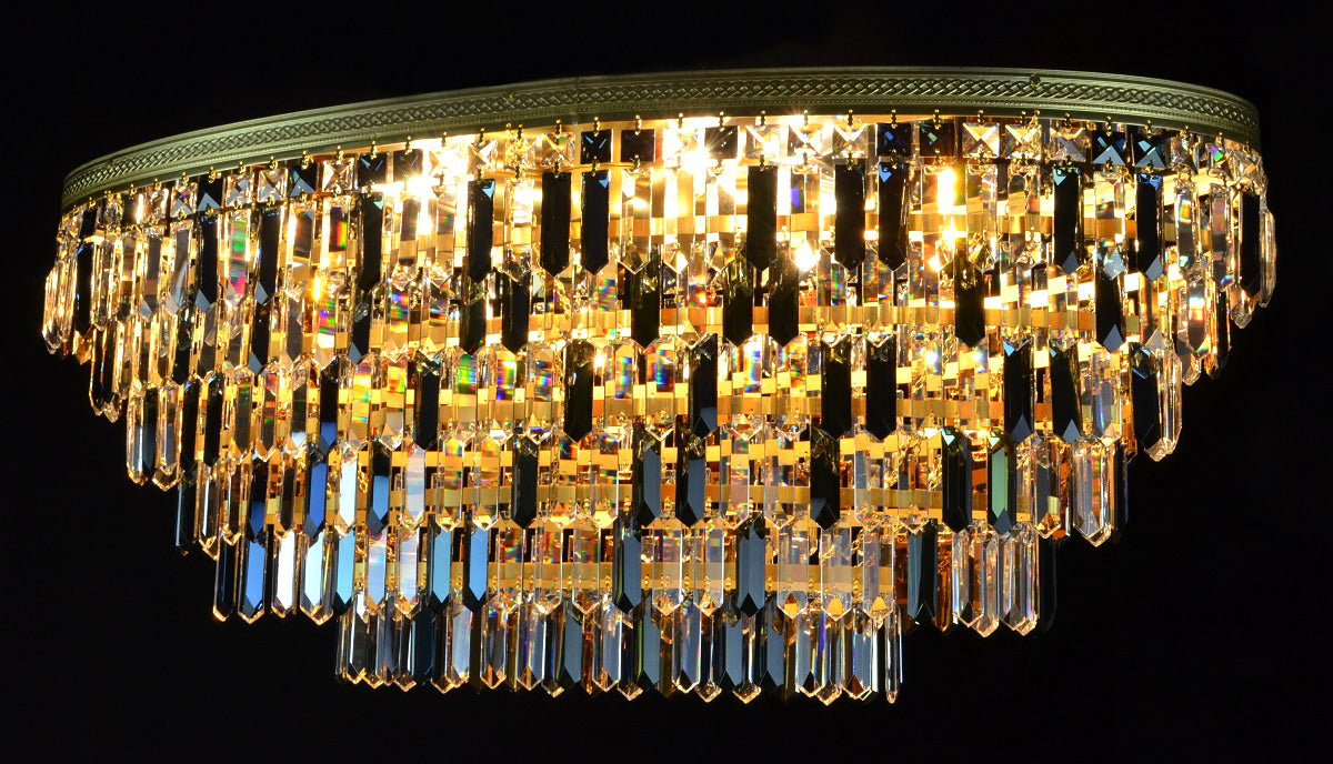 Gros plan du lustre cristal doré, rangées de prismes allumés sur fond noir
