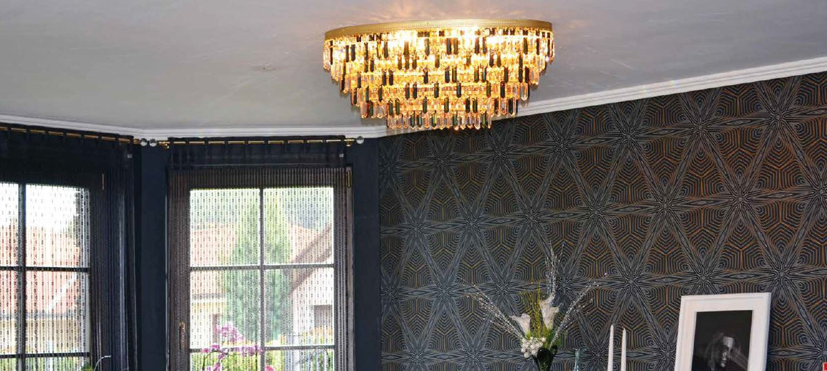 Lustre installé au plafond d'un salon, papier peint géométrique et grandes fenêtres