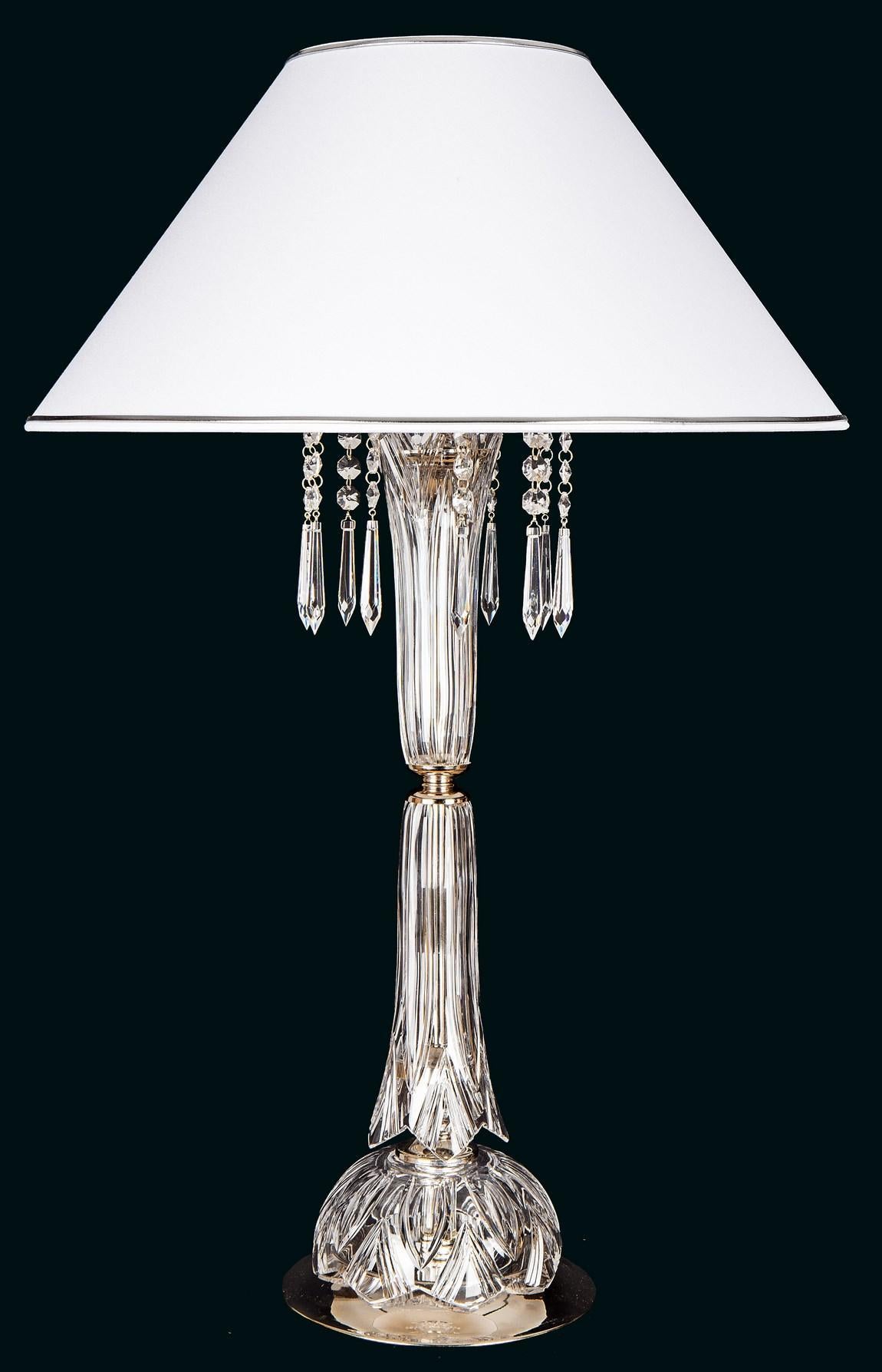 Lampe à poser de face, abat-jour conique blanc, pampilles de cristal et base cannelée transparente.