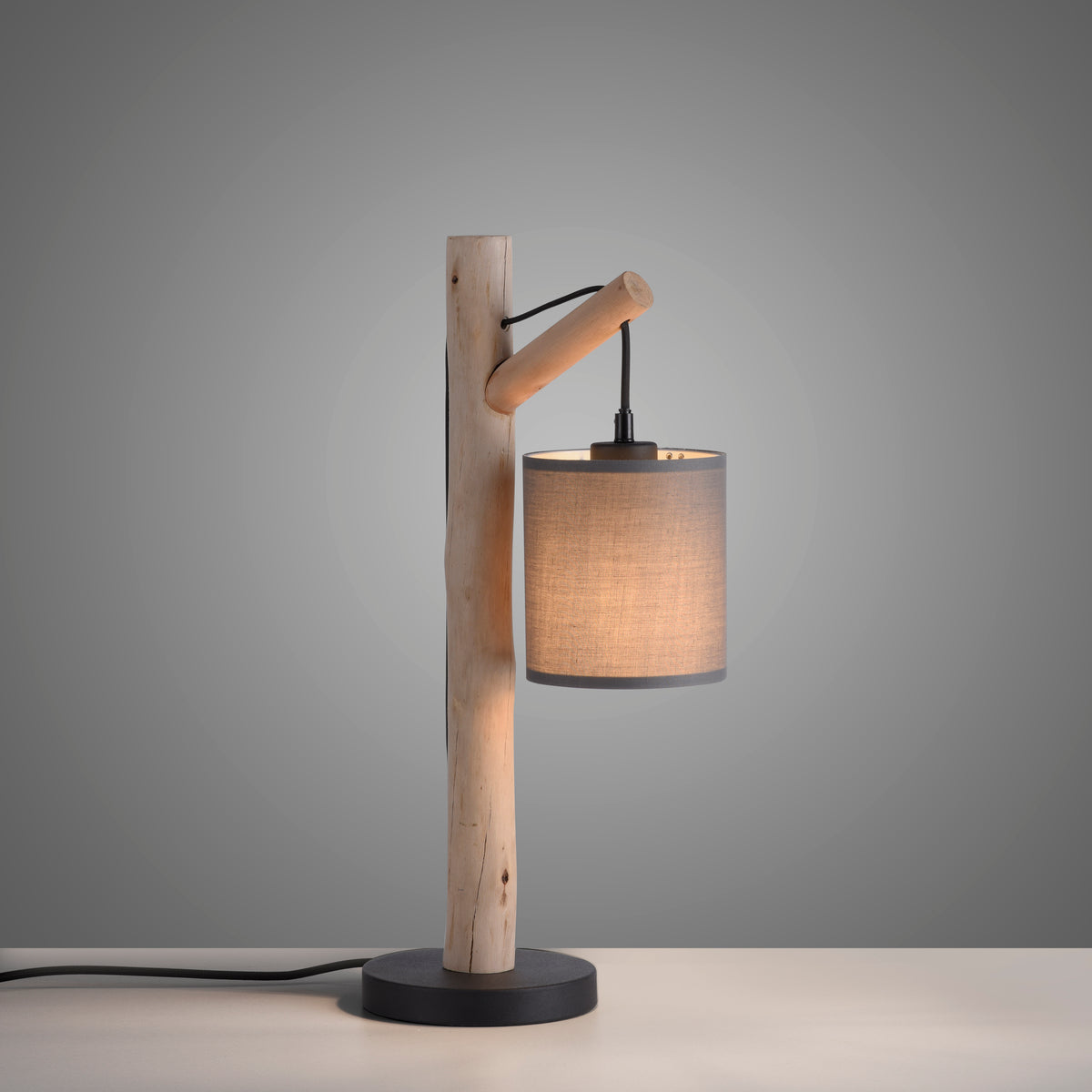 Gros plan du luminaire allumé sur fond gris avec câble d'alimentation visible