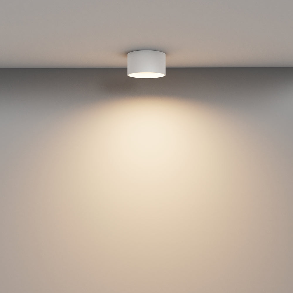Mise en ambiance : petit plafonnier blanc fixé au plafond diffusant un halo lumineux