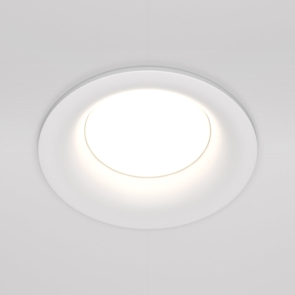 Spot encastré blanc allumé, vue de face dans un plafond blanc