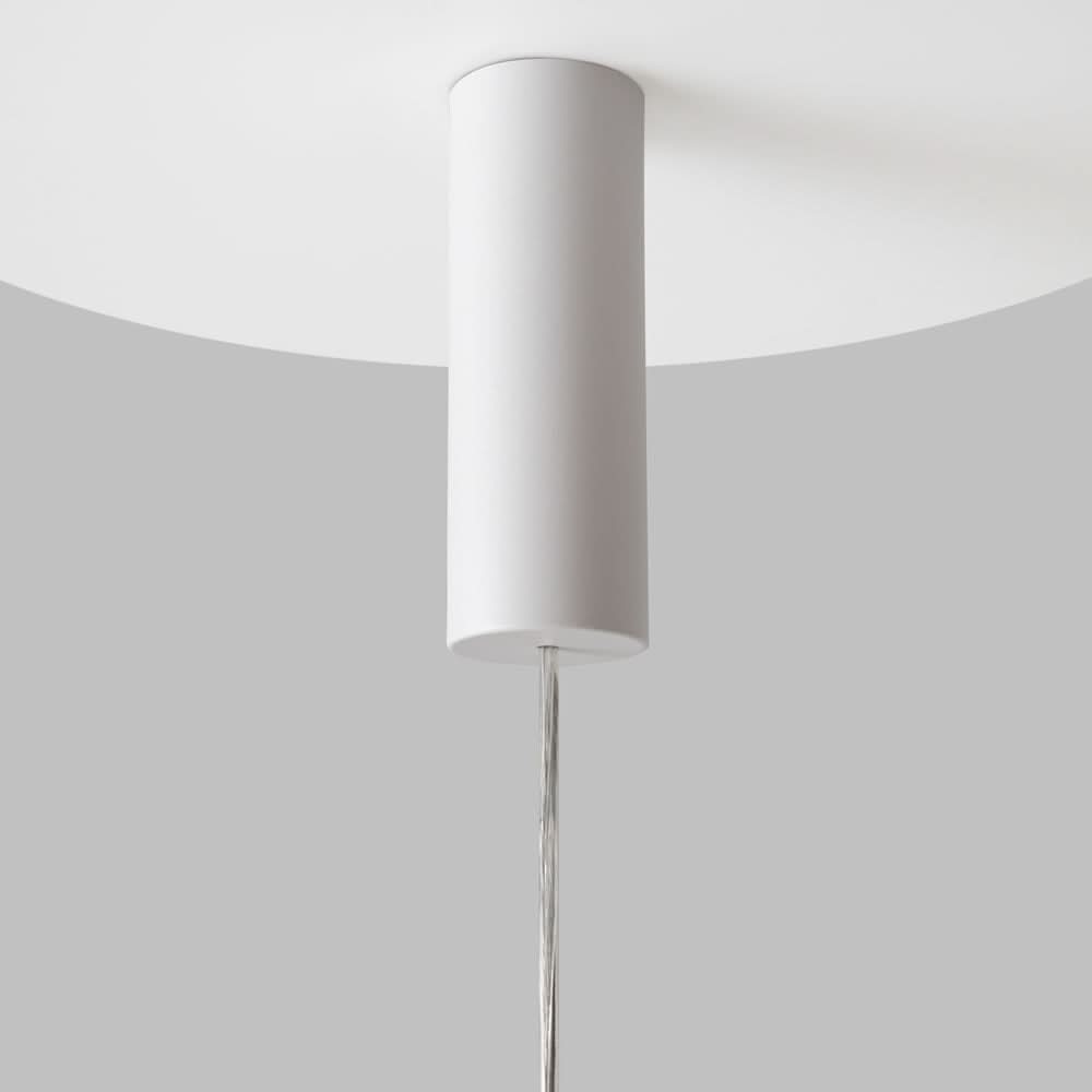 Gros plan de la fixation au plafond, cylindre blanc et câble métallique tendu.