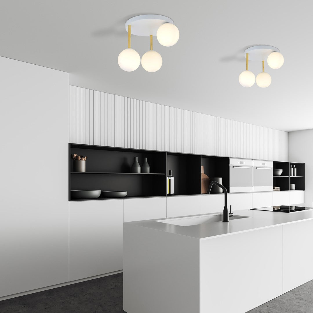 Deux plafonniers éclairant une cuisine blanche minimaliste avec îlot central et rangements
