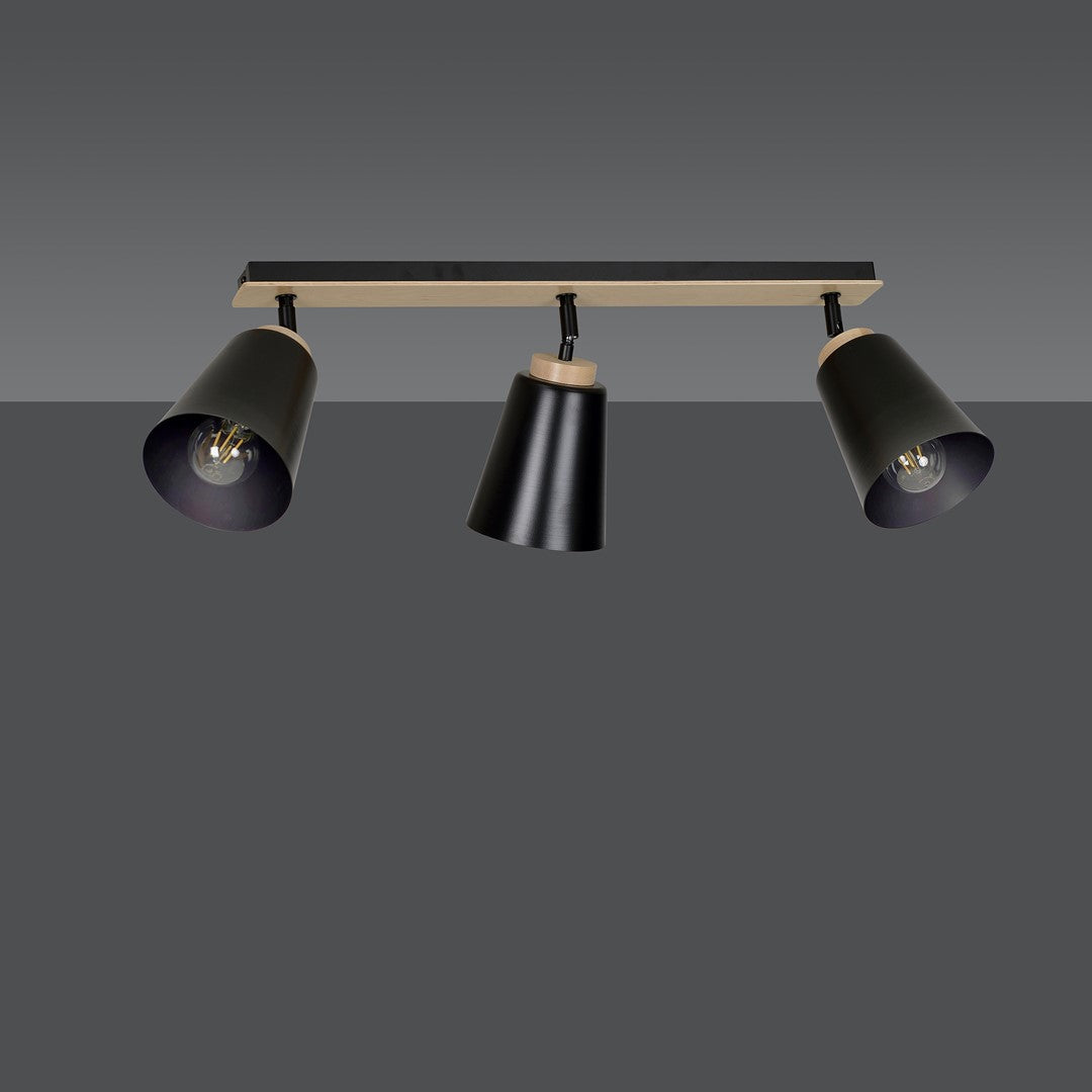 Vue du luminaire allumé face à un mur gris, trois spots orientables