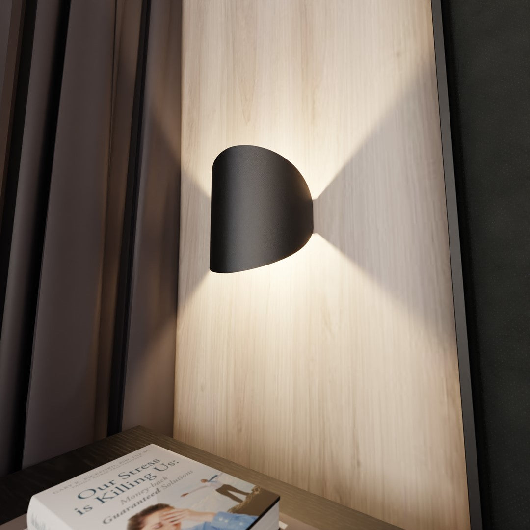 Détail rapproché de l'applique noire projetant un halo lumineux vertical.