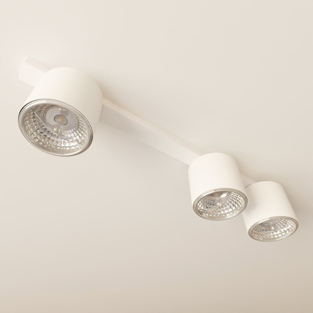 Gros plan sur un spot cylindrique blanc allumé, réflecteur strié et ampoule visible.