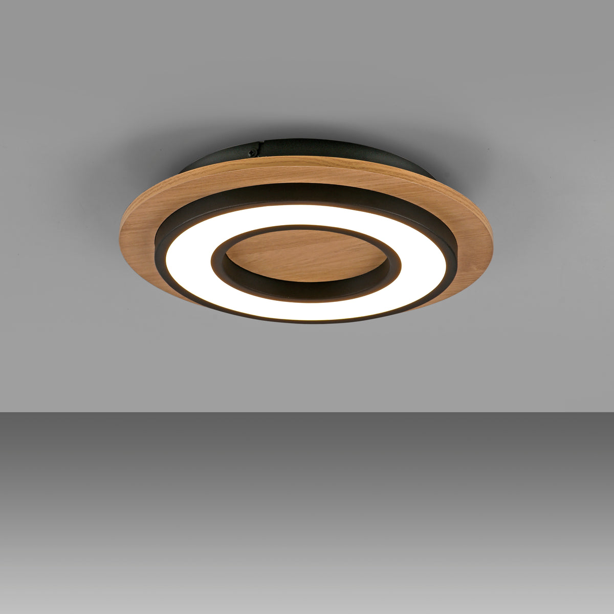 Vue plongeante du plafonnier allumé projetant un halo lumineux sur fond gris