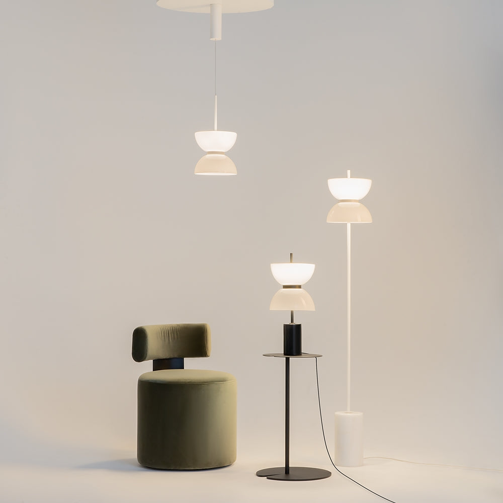 Mise en ambiance avec trois luminaires de la collection et un fauteuil vert.