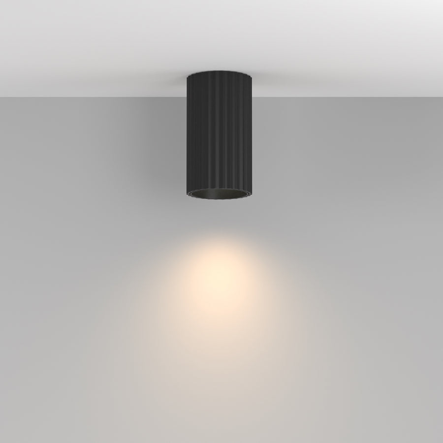 Vue en situation du plafonnier noir allumé projetant un halo lumineux sur le mur