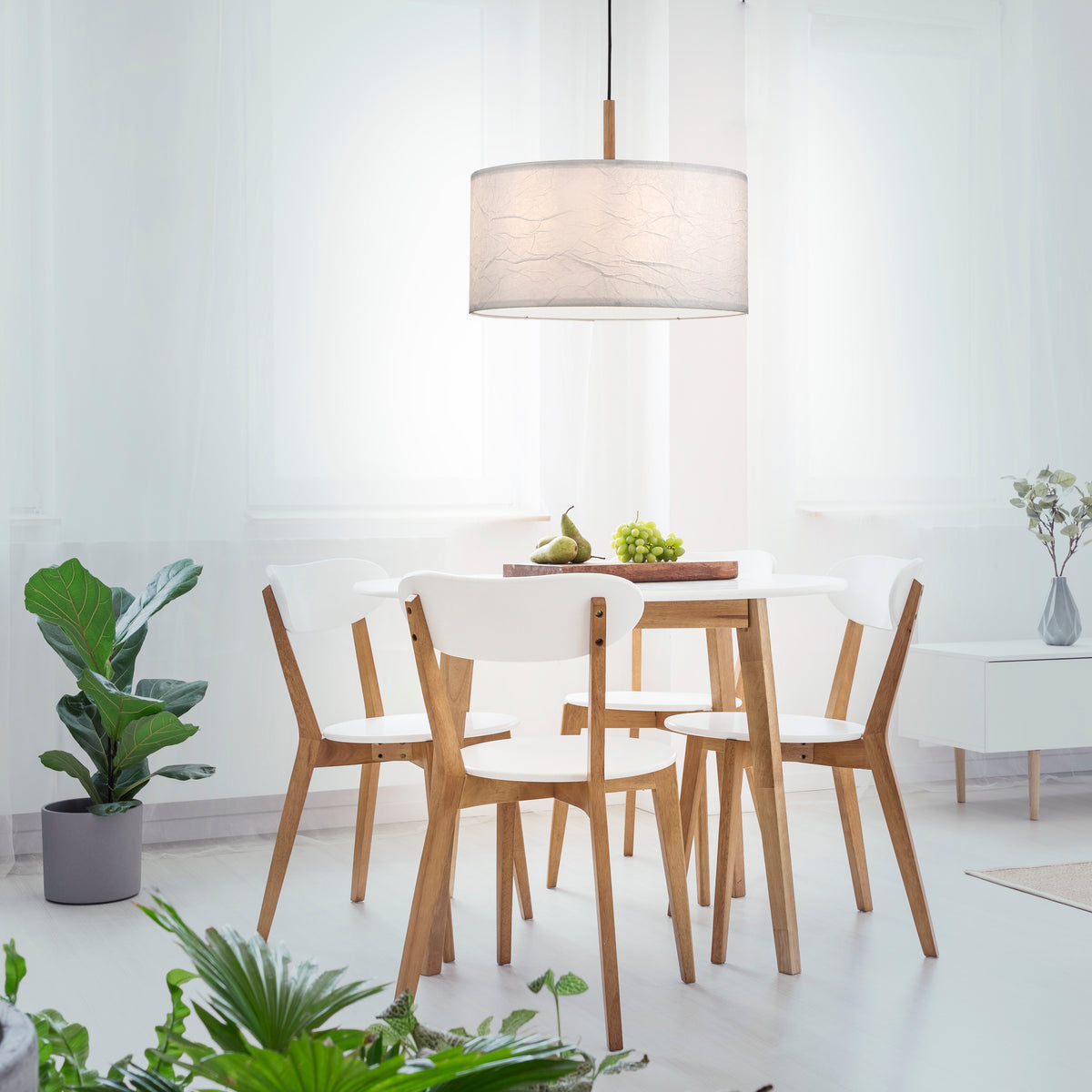 Mise en ambiance salle à manger lumineuse avec table en bois, chaises blanches et plantes vertes