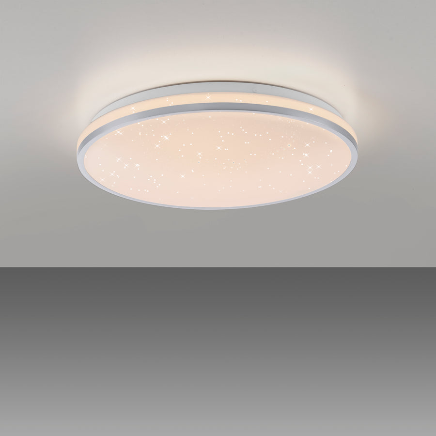 Plafonnier rond allumé fixé au plafond, diffusant une lumière chaude avec effet étoilé.