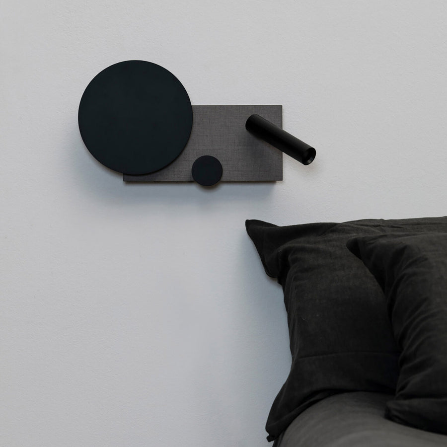 Vue de face de l'applique noire et grise sur un mur blanc