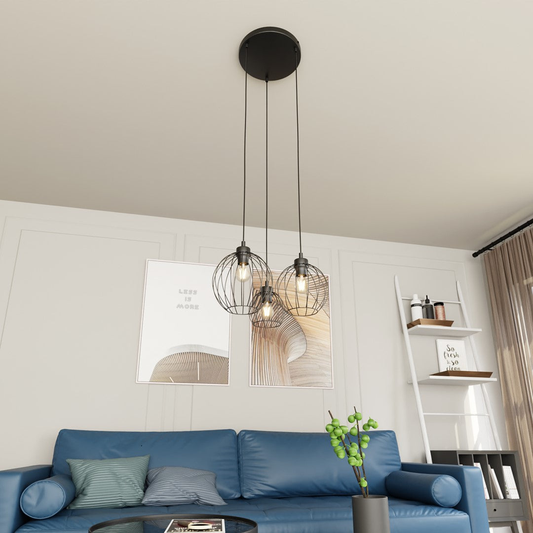 Mise en ambiance salon avec canapé bleu, suspension noire à trois cages au plafond.