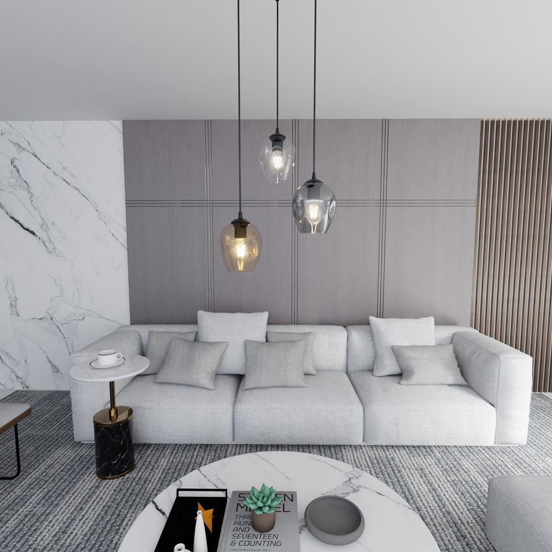 Mise en ambiance salon, suspension trois lumières devant un canapé gris et mur en marbre.