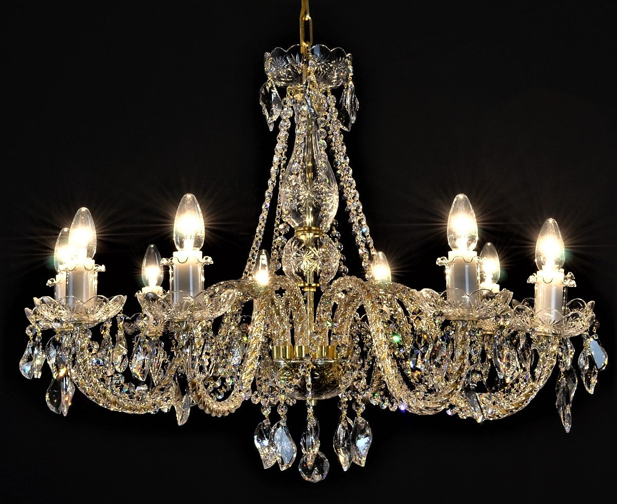 Lustre en cristal à bras dorés de face sur fond noir, ampoules allumées