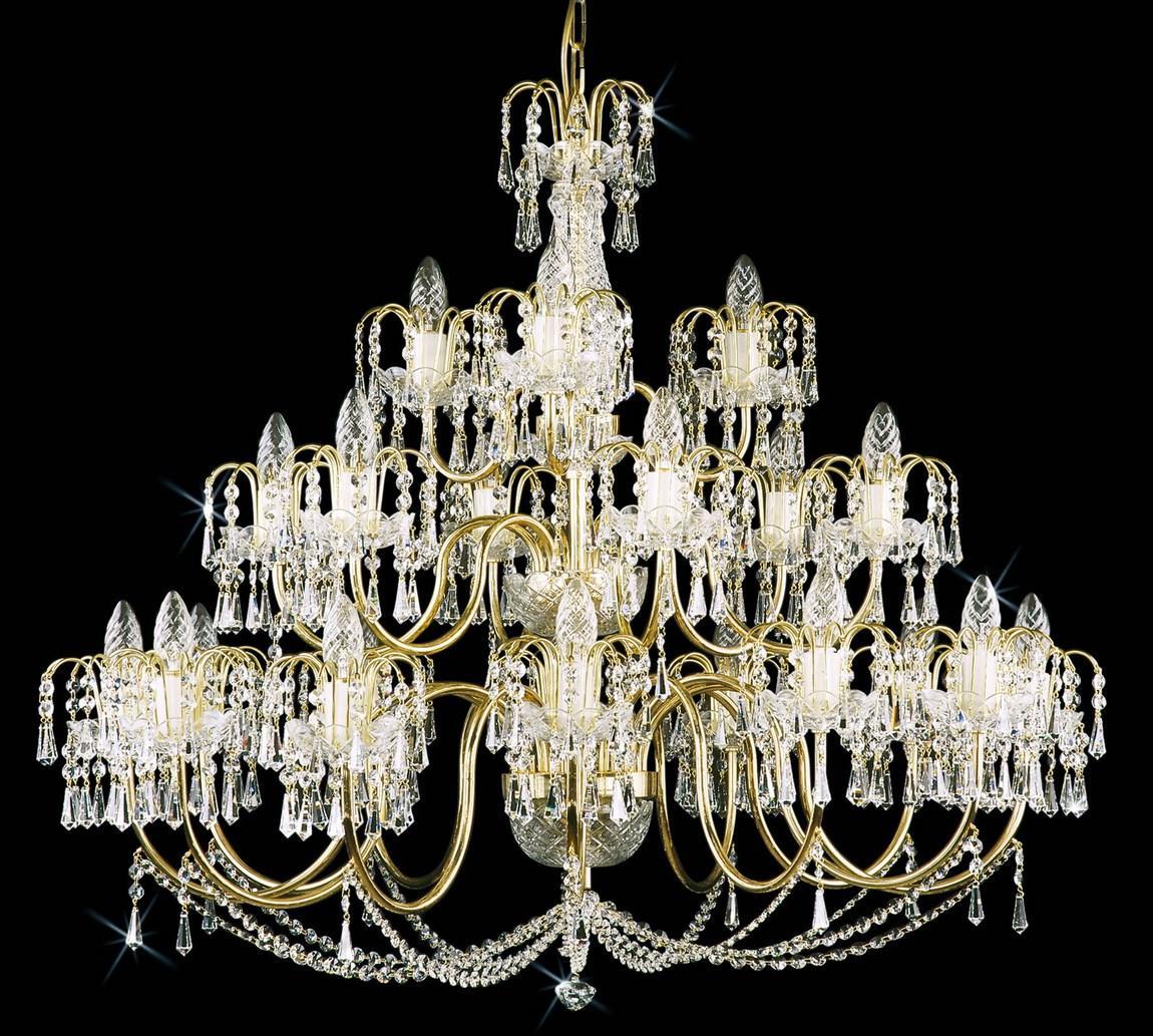 Lustre en cristal à monture dorée, étages de bras, pendeloques et gouttes scintillantes sur fond noir.